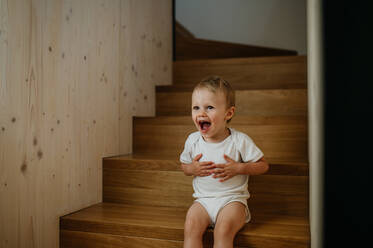 Ein süßes kleines Mädchen, das zu Hause auf der Treppe sitzt. - HPIF04423