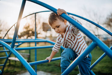 Ein kleiner Junge spielt auf einem Spielplatz im Freien. - HPIF04427