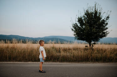 Ein kleiner Junge steht im Sommer auf einem Weizenfeld - HPIF04432