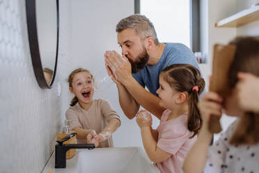 Ein Vater hat Spaß daran, mit seinen kleinen Töchtern im Badezimmer Seifenblasen zu machen. - HPIF04444