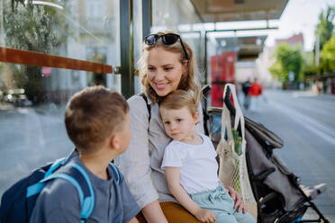 A young mother with little kids waiting on bus stop in city. - HPIF04451