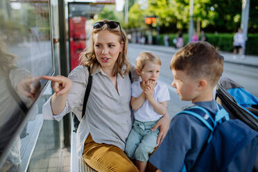 Eine junge Mutter mit kleinen Kindern wartet an einer Bushaltestelle in der Stadt. - HPIF04456