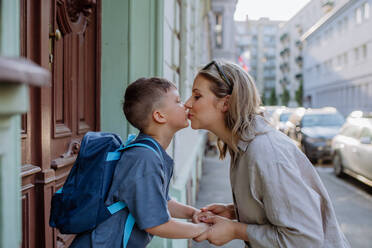 Eine Mutter küsst ihren kleinen Sohn auf dem Weg zur Schule, und eine Mutter und ein Junge verabschieden sich vor der Schule. - HPIF04460