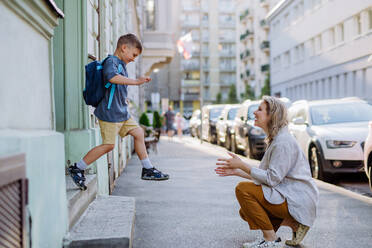 A young mother waiting for her little son on streetafter school, little boy is running to hug her. - HPIF04463