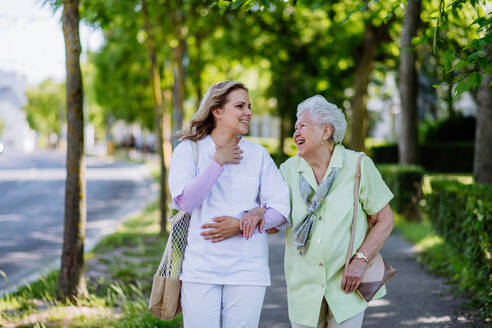 Portrait of caregiver with senior woman on walk in park. - HPIF04491
