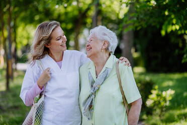 Porträt eines Pflegers mit einer älteren Frau beim Spaziergang im Park. - HPIF04495