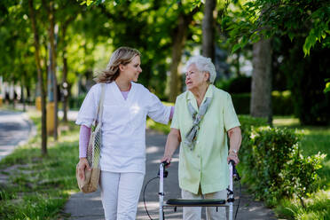 Portrait of caregiver with senior woman on walk in park. - HPIF04500