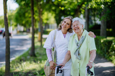 Portrait of caregiver with senior woman on walk in park. - HPIF04504