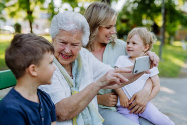 A great grandmother taking selfie with her granddaughter and kids when sitting in park in summer. - HPIF04527