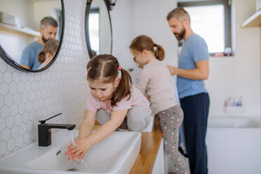 Ein Vater mit drei kleinen Kindern im Badezimmer, Konzept der Morgenroutine. - HPIF04563