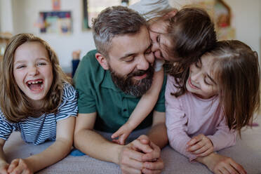 A cheerful father with three little daughters playing together at home. - HPIF04580