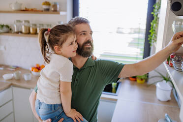 Ein kleines Mädchen mit ihrem Vater in der Küche zu Hause, tägliche Hausarbeit Konzept. - HPIF04589