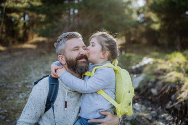 A little daughter kissing her father during walk in spring nature together. - HPIF04590