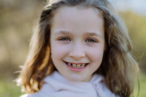 Portrait of pretty child girl standing in summer park looking in camera smiling happily. - HPIF04593