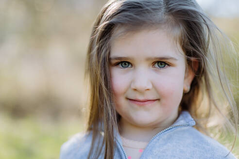 Portrait of pretty child girl standing in summer park looking in camera smiling happily. - HPIF04594