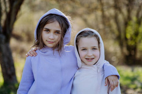 Two little sisters looking at a camera in spring nature together. - HPIF04596