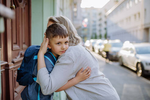 Eine Mutter umarmt ihren kleinen Sohn auf dem Weg zur Schule, und eine Mutter und ein Junge verabschieden sich vor der Schule. - HPIF04605