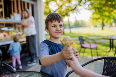 Kleiner Junge mit seiner Mutter und seiner Schwester, die an einem heißen Sommertag ein Eis im Park genießen. - HPIF04609