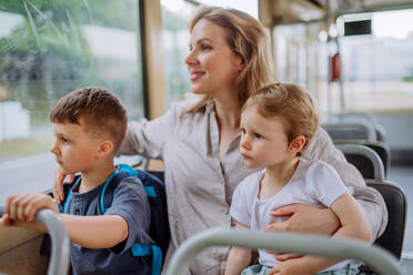 Eine junge Mutter mit kleinen Kindern, die im Sommer mit der Straßenbahn fährt, um zu pendeln und einen nachhaltigen Lebensstil zu pflegen. - HPIF04610