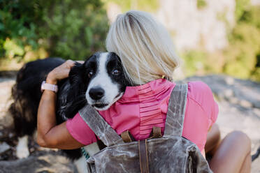 Senior woman resting and hugging her dog during walking in a forest. - HPIF04683