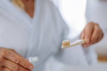 A close-up of woman holding wooden toothbrush and natural toothpaste in bathroom, sustainable lifestyle. - HPIF04713