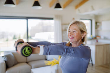 A fit senior woman exercising with dumbbells at home, active lifestyle concept. - HPIF04737