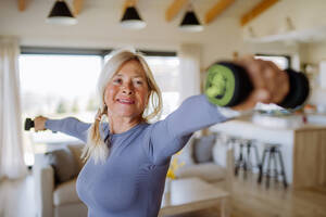 A fit senior woman exercising with dumbbells at home, active lifestyle concept. - HPIF04741