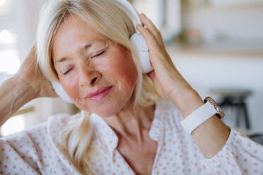 A senior woman with headphones listening to relaxation music at home - HPIF04743