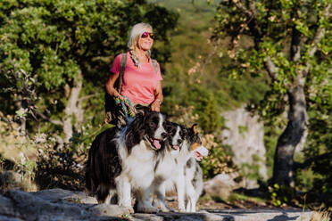 Senior woman walking with her three dogs in a forest. - HPIF04767