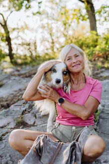 Porträt einer älteren Frau mit ihrem Hund in einem Wald. - HPIF04778