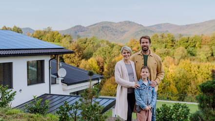 Happy family near their house with a solar panels. Alternative energy, saving resources and sustainable lifestyle concept. - HPIF04781