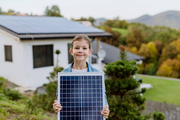 Kleines Mädchen, das ein Photovoltaik-Solarpanel in der Hand hält: Alternative Energie, Ressourcenschonung und nachhaltiger Lebensstil. - HPIF04814
