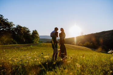 Eine glückliche junge Familie, die draußen in der grünen Natur Zeit miteinander verbringt. - HPIF04886