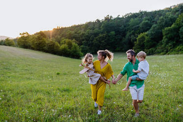 Eine glückliche junge Familie, die draußen in der grünen Natur Zeit miteinander verbringt. - HPIF04889