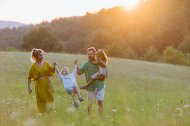 Eine glückliche junge Familie, die draußen in der grünen Natur Zeit miteinander verbringt. - HPIF04895
