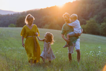 Eine glückliche junge Familie, die draußen in der grünen Natur Zeit miteinander verbringt. - HPIF04896