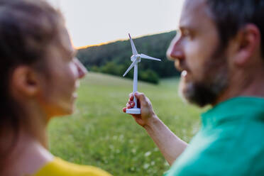 Ein Paar in der Natur mit einem Modell einer Windkraftanlage. Konzept der ökologischen Zukunft und der erneuerbaren Ressourcen. - HPIF04903