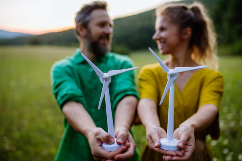 A couple standing in nature with model of wind turbine. Concept of ecology future and renewable resources. - HPIF04909