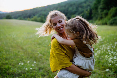 Eine glückliche Mutter verbringt Zeit mit ihrer kleinen Tochter draußen in der grünen Natur. - HPIF04911