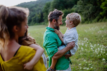 Eine glückliche junge Familie, die draußen in der grünen Natur Zeit miteinander verbringt. - HPIF04912