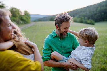 Eine glückliche junge Familie, die draußen in der grünen Natur Zeit miteinander verbringt. - HPIF04913