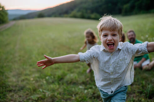 Glückliche junge Familie, die ihre Zeit gemeinsam draußen auf der Wiese verbringt, ein kleiner Junge, der rennt und die Natur genießt. - HPIF04918