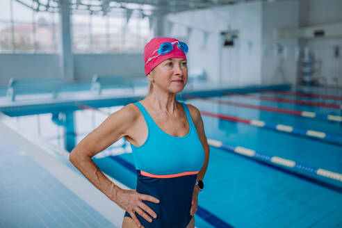 Eine aktive ältere Frau, die sich auf das Schwimmen im Hallenbad vorbereitet. - HPIF04931