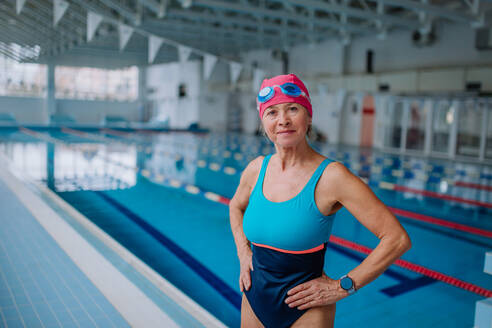 Eine aktive ältere Frau schaut in die Kamera und lächelt nach dem Schwimmen im Hallenbad. - HPIF04937
