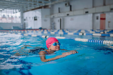 Eine aktive ältere Frau beim Schwimmen in einem Hallenbad. - HPIF04964