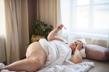 A sick overweight woman lying in bed at home. - HPIF04989