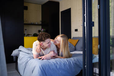 A Young happy couple in love lying in bed in morning in their new home in tiny house,sustainable living concept. - HPIF04999