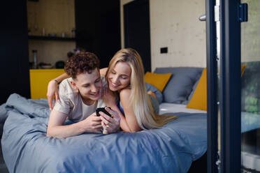 Ein junges, glückliches, verliebtes Paar liegt morgens in ihrem neuen Haus in einem winzigen Haus, einem nachhaltigen Wohnkonzept, im Bett. - HPIF05000