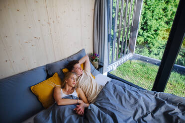 Ein junges, glückliches, verliebtes Paar liegt morgens in ihrem neuen Haus in einem winzigen Haus, einem nachhaltigen Wohnkonzept, im Bett. - HPIF05004