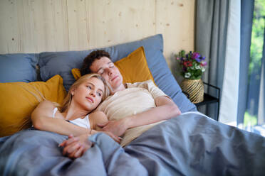 A young happy couple in love lying in bed in morning in their new home in tiny house, sustainable living concept. - HPIF05005